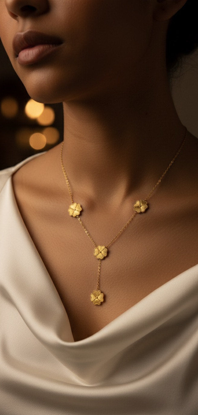 Gold necklace with floral pendants on a person wearing a white garment.