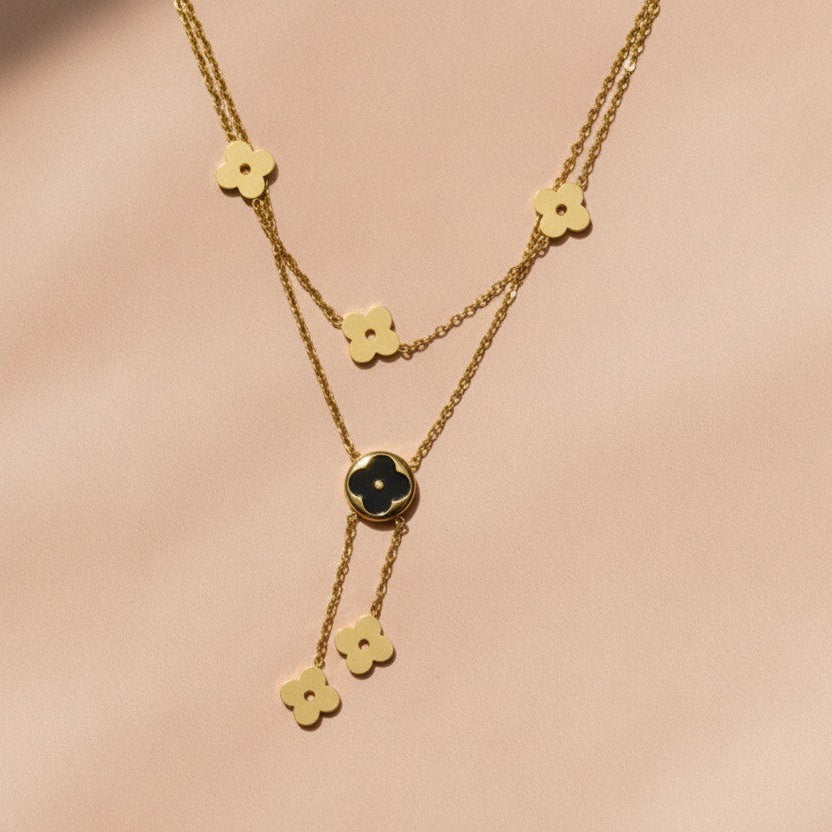 Gold necklace with floral pendants on a beige background