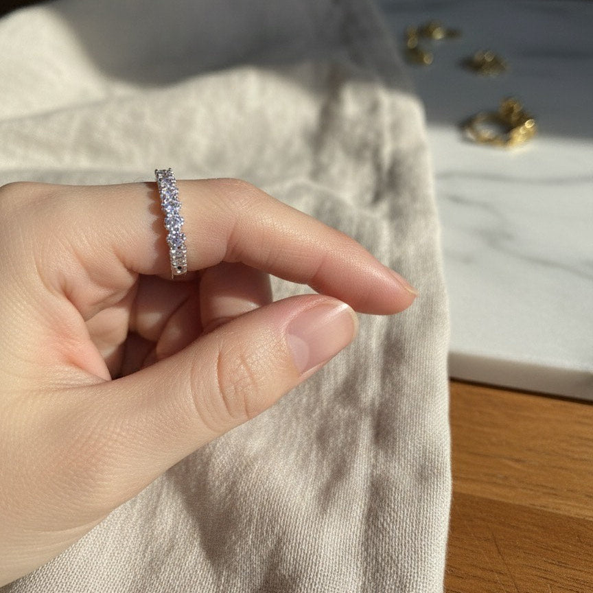 Hand wearing a silver ring with sunlight casting shadows on a textured surface.