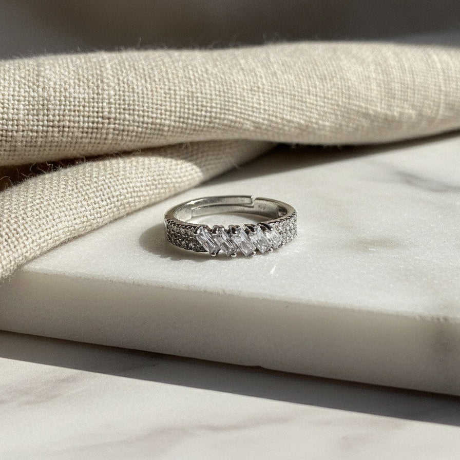 Silver ring with gemstones on a marble surface with fabric background