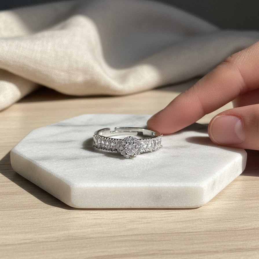 Silver ring on a marble coaster with a hand reaching towards it