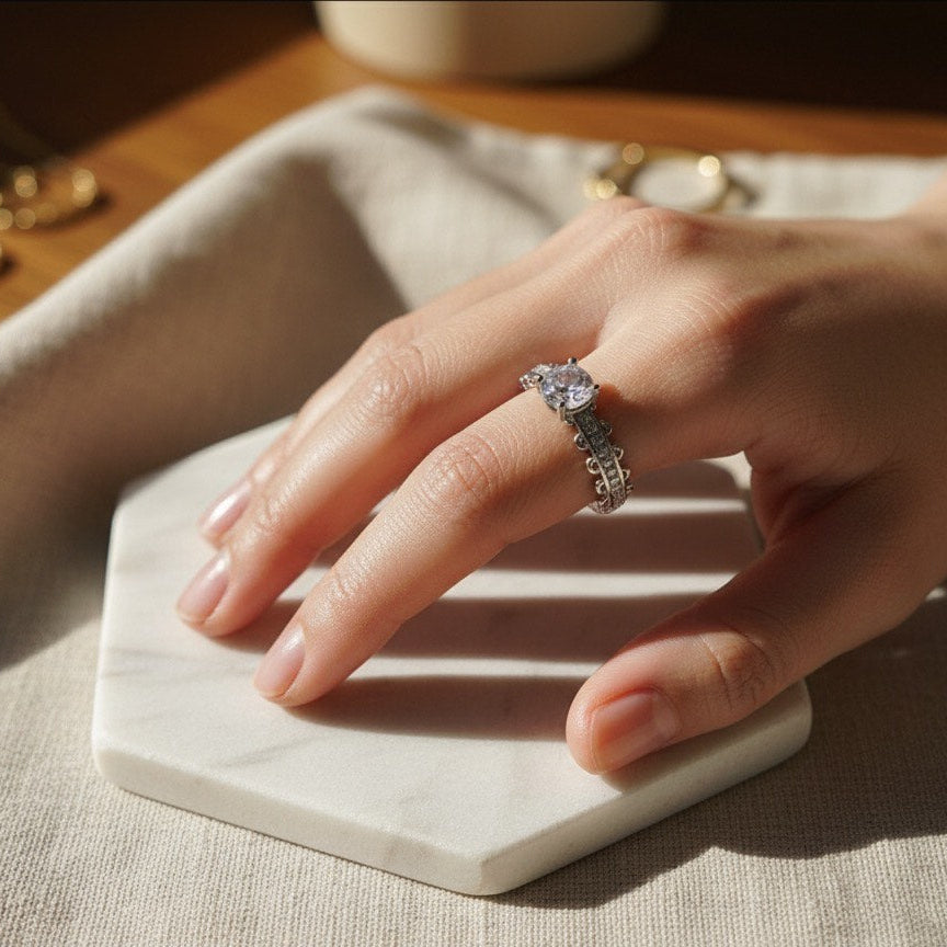 Hand wearing a ring on a marble coaster with soft lighting