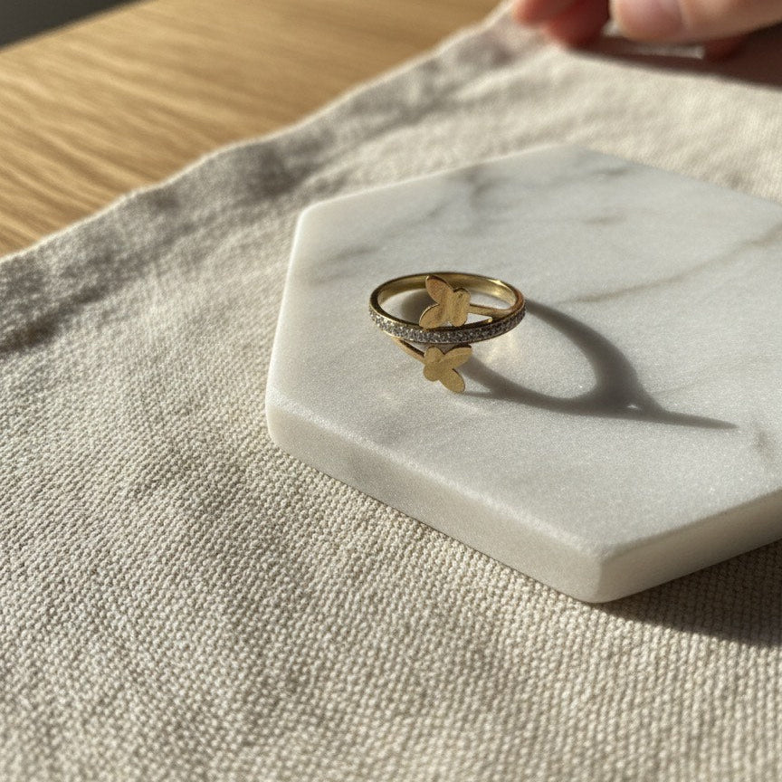 Gold ring with a leaf design on a marble coaster