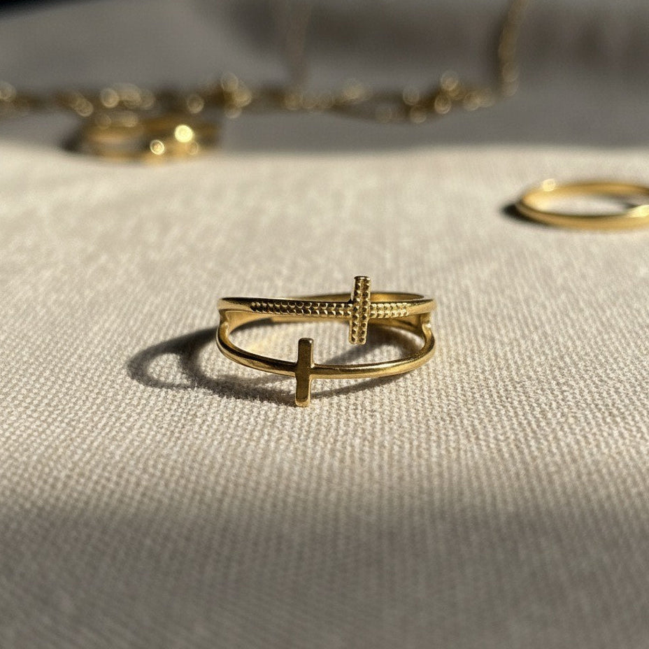 Gold ring with a cross design on a textured surface