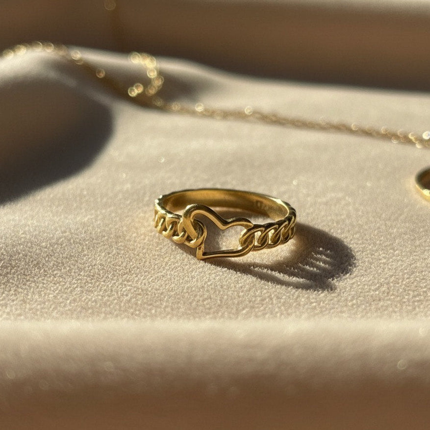 Gold ring with chain design on a beige fabric background