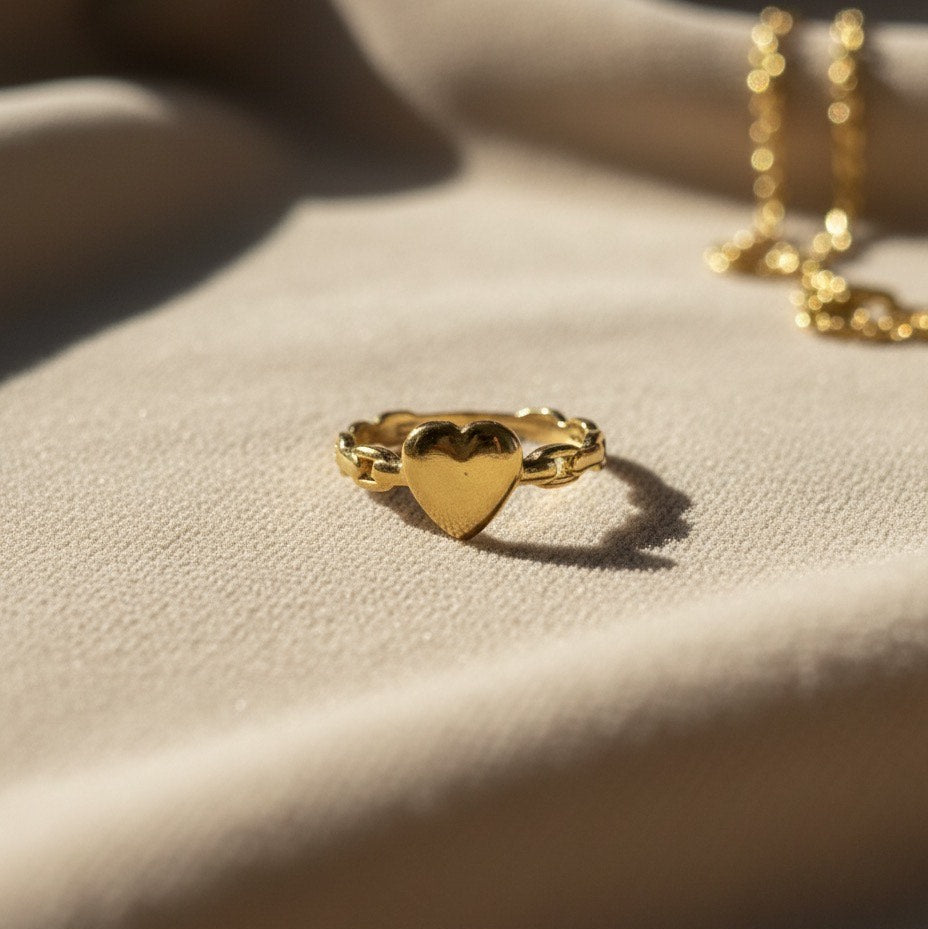 Gold heart-shaped ring on a beige fabric surface