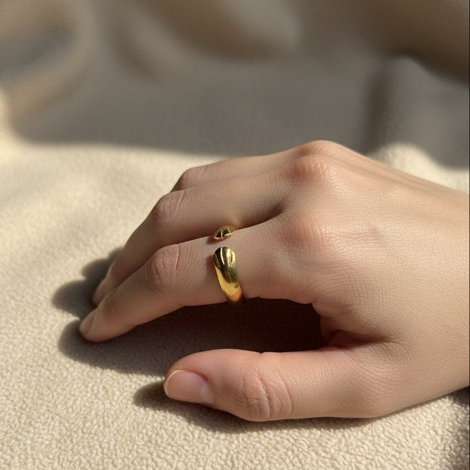 Hand wearing a gold ring on a beige fabric background