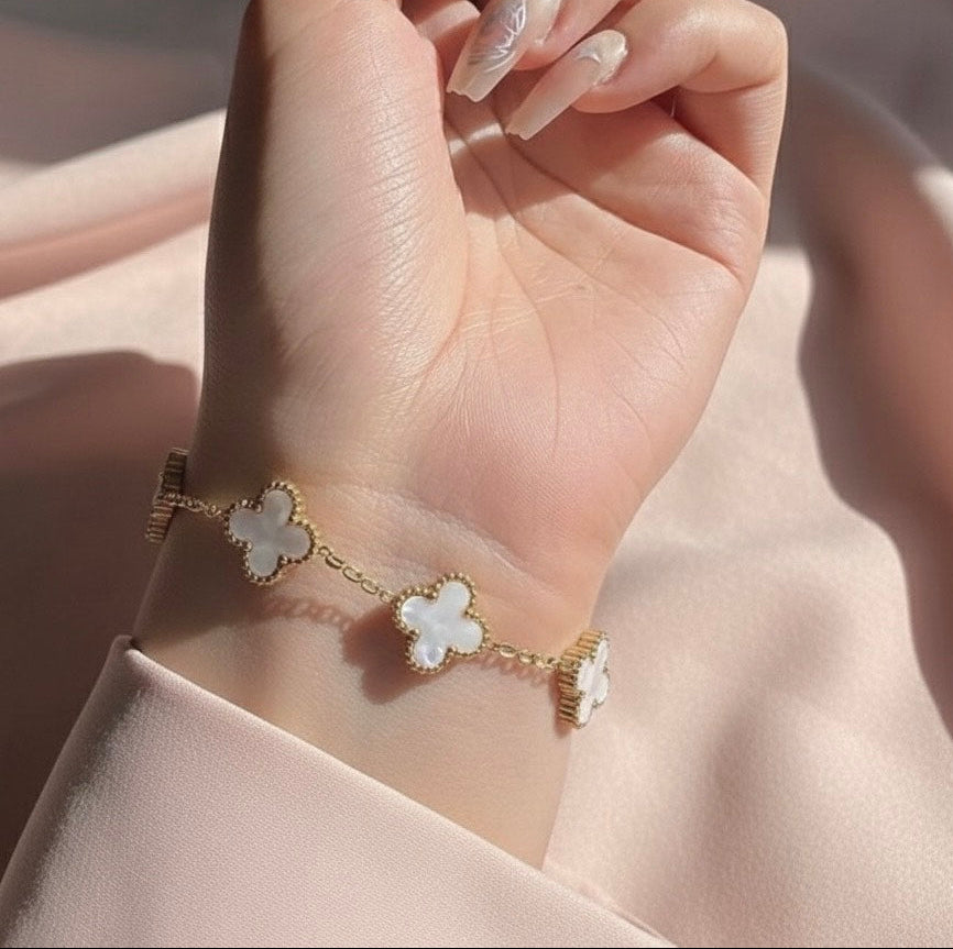 Hand wearing a delicate bracelet with floral designs on a soft background