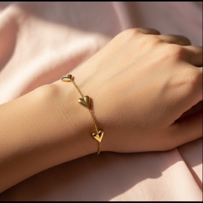 Gold bracelet on a wrist with a soft pink fabric background