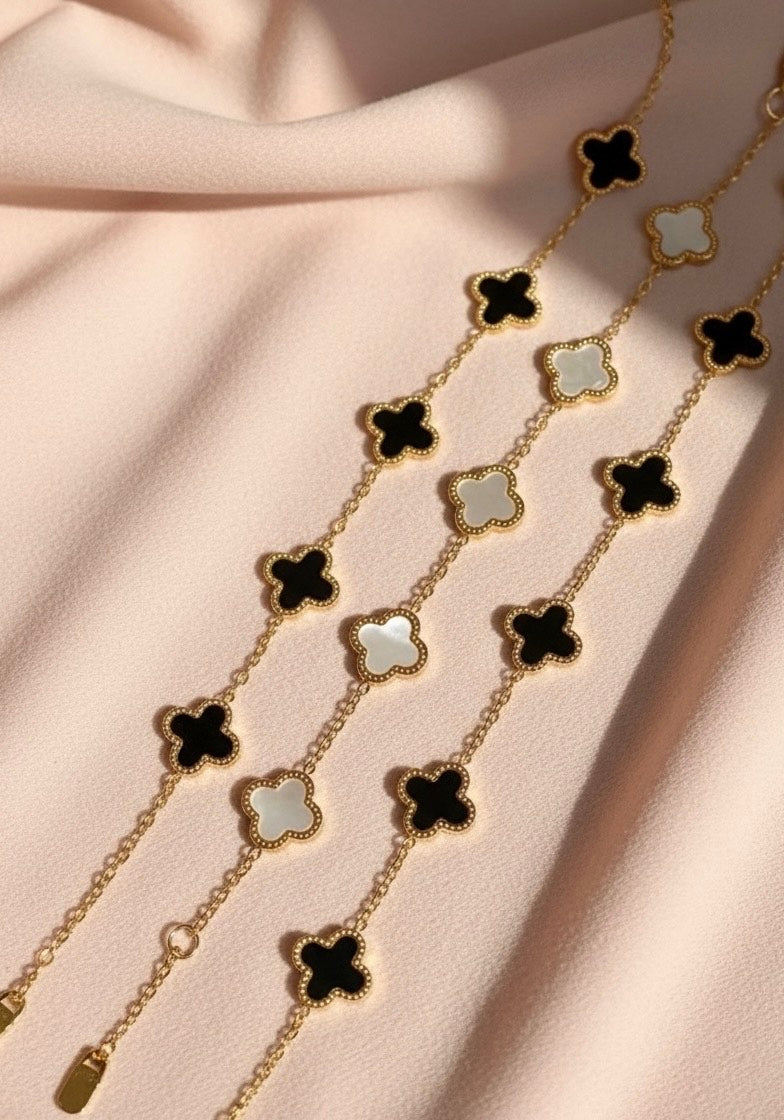 Necklace with black and white clover-shaped pendants on a beige fabric background