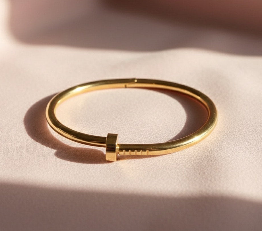Gold bracelet on a light pink surface