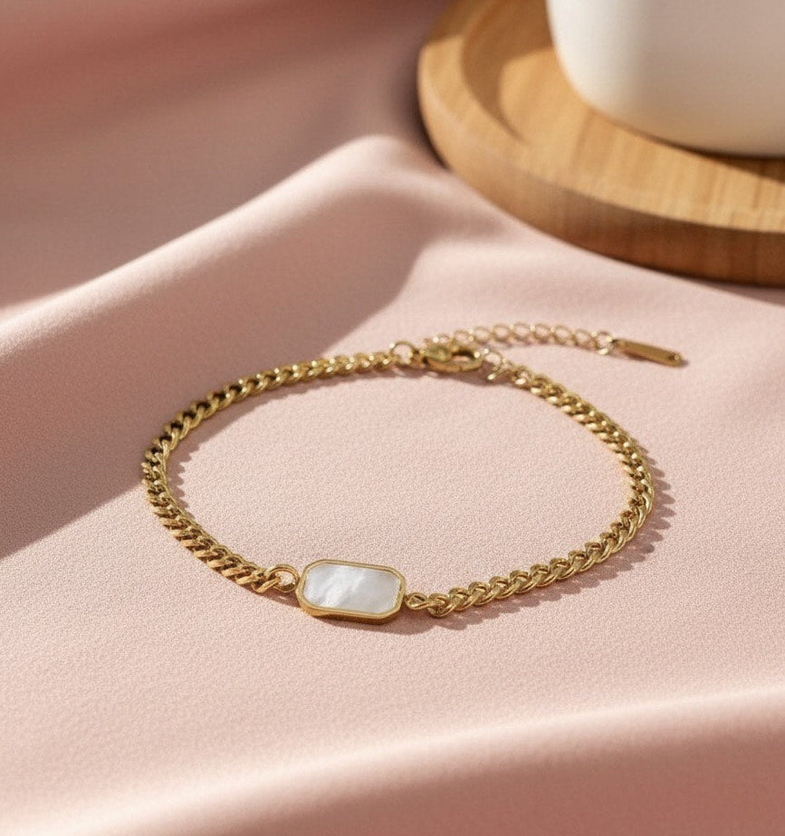 Gold bracelet with a gemstone on a pink fabric background