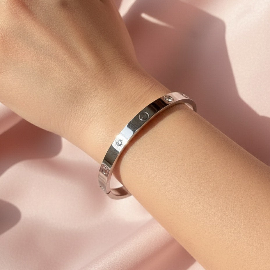 Silver bracelet on a wrist against a soft pink background