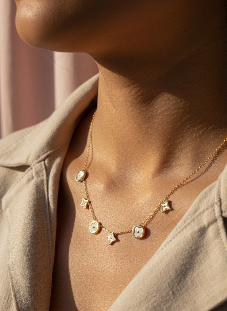 Necklace with star-shaped pendants worn by a person against a neutral background