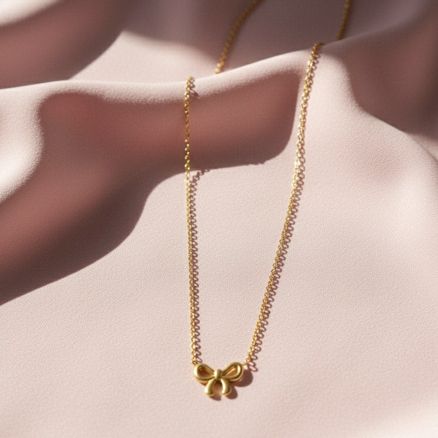 Gold necklace with a delicate pendant on a soft pink fabric background